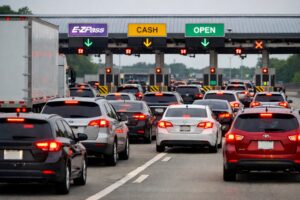 Vehicles braking and compressing together as traffic slows rapidly approaching an E-ZPass toll plaza, illustrating how sudden speed reduction increases rear end collision risk.