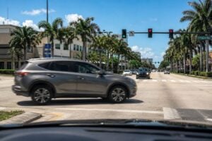 Mid-size SUV making a left turn across an intersection in South Florida with oncoming traffic visible in the distance