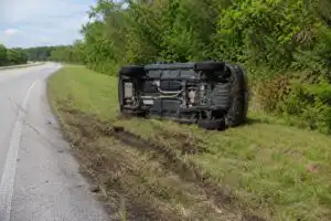 An SUV rolled onto its side in a grassy ditch beside a Florida highway