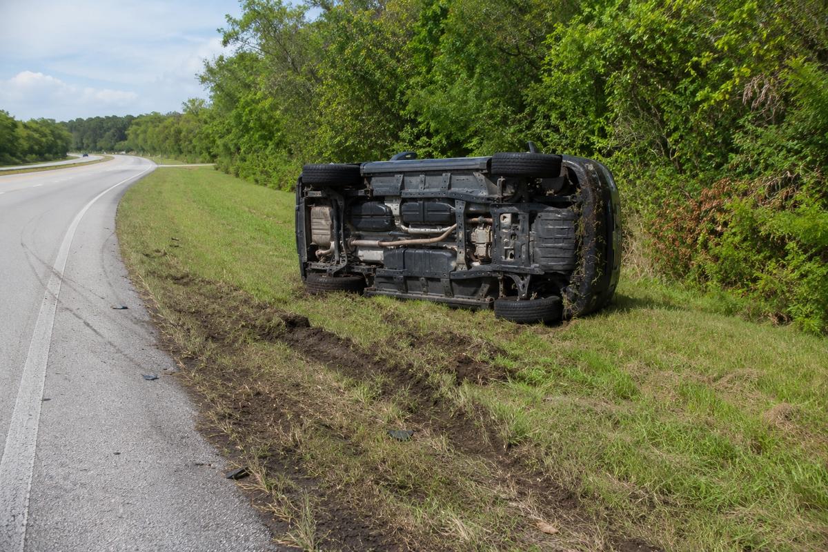 An SUV rolled onto its side in a grassy ditch beside a Florida highway