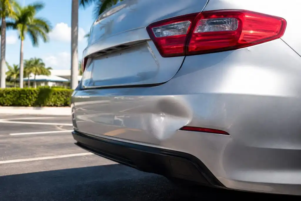 Small dent and scratches on a car bumper after a minor Florida accident